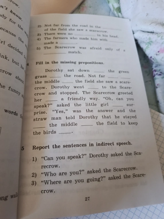 Fill in the missing prepositions. Dorothy sat down ___ the green grass ___ the road.